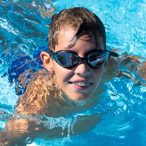 Young boy swimming with metal braces.