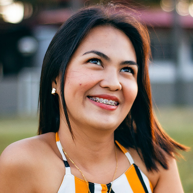 Girl smiling and looking upward while wearing braces.