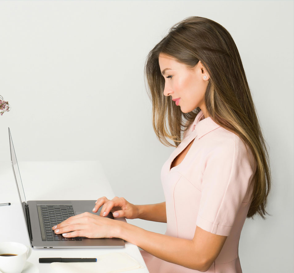 A female nurse typing on a computer to communicate a referral